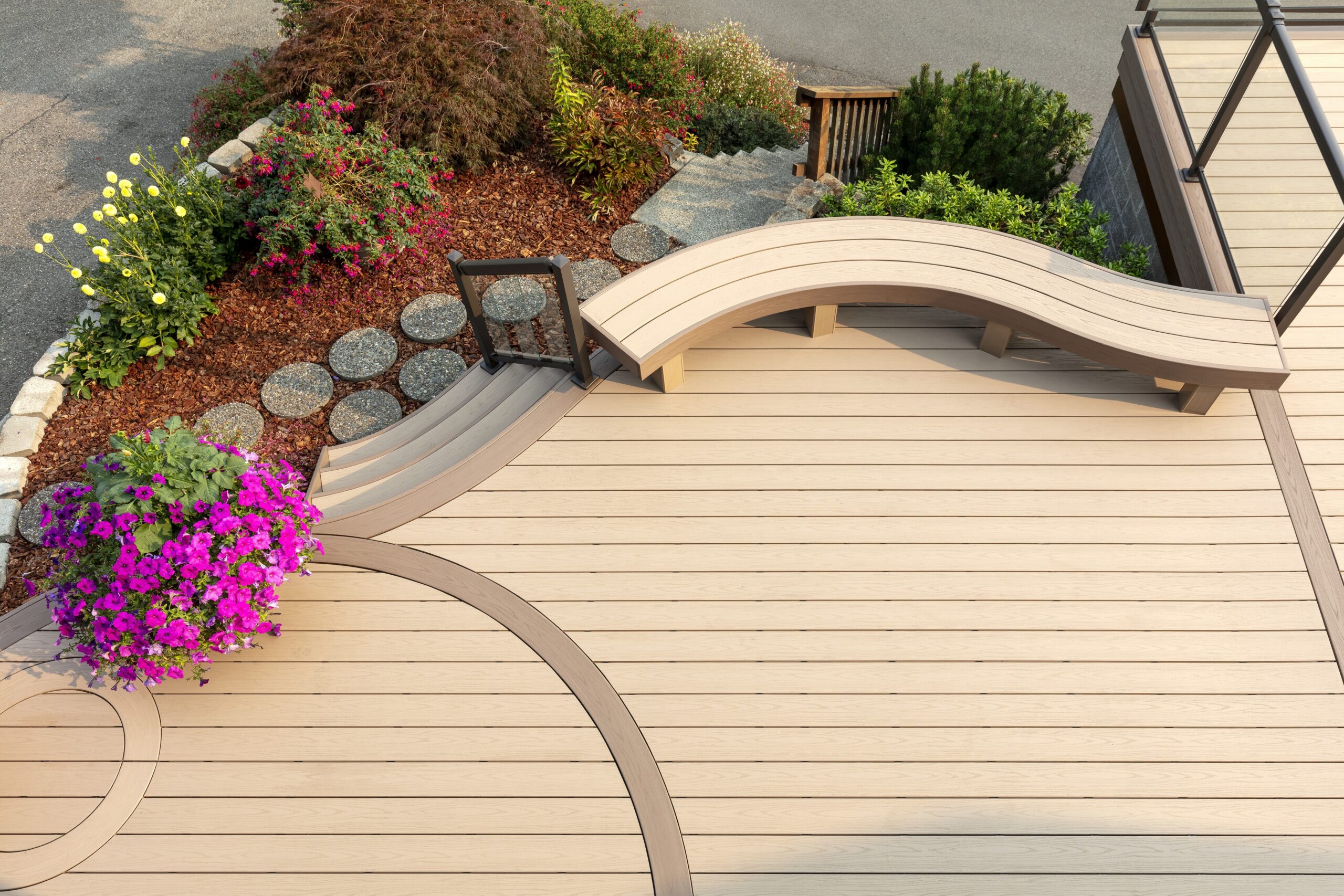 Overhead view of a curved TimberTech deck in Harvest color with built-in bench and garden landscaping